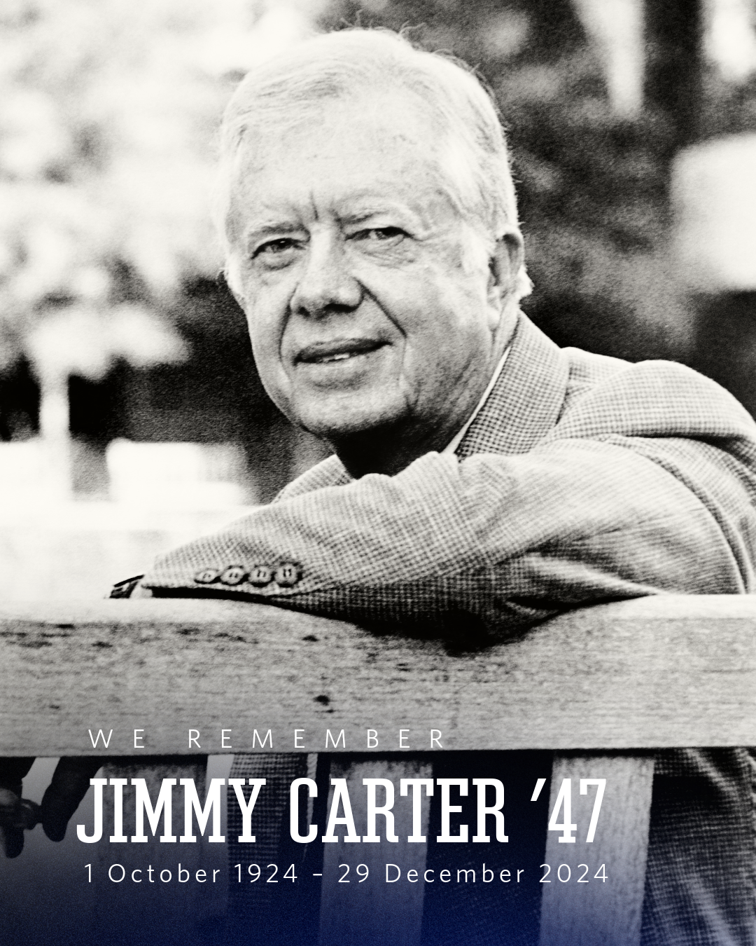 Jimmy Carter sitting on a bench turned so that he is facing the back of the bench, with his arm up on the back of the bench.